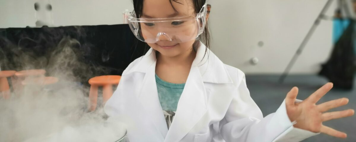 a little girl wearing a white lab coat and goggles