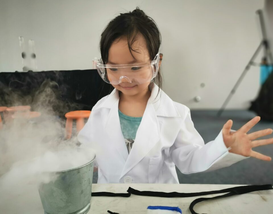 a little girl wearing a white lab coat and goggles
